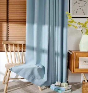 Light blue 900g embossed blackout curtain fabric hanging in a room, available for wholesale