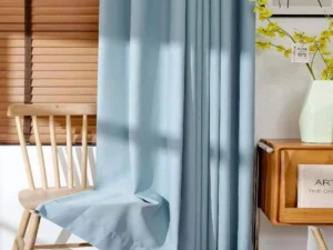 Light blue 900g embossed blackout curtain fabric hanging in a room, available for wholesale