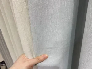 Hand holding soft faux linen drapery fabric with 90% blackout performance, wholesale supply