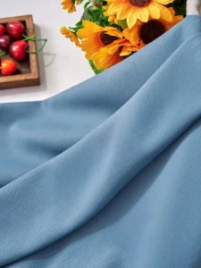 Soft blue room darkening curtain fabric displayed with sunflowers. We supply 280cm to 320cm seamless width rolls directly from our China factory with fast global shipping.