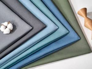 Close up texture of folded 85% blackout curtain materials in blue, grey, and green. Factory direct supply in bulk rolls with 280cm to 320cm seamless width.
