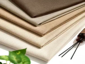 Close-up of stacked heavyweight cotton-linen blend blackout curtain fabrics in natural earth tones, showing thick 1400gsm texture for wholesale.