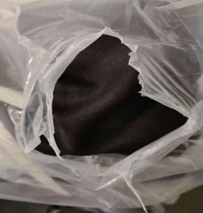 Close up texture of dark bulk faux linen blackout curtain fabric in warehouse packaging`